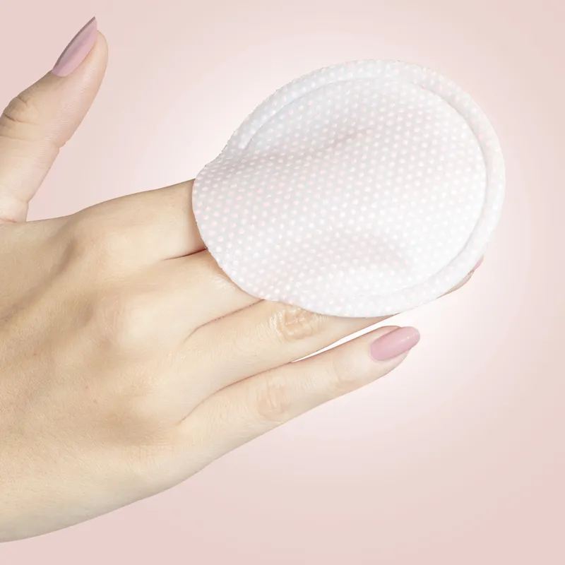 Hand hält eine runde, gepunktete Gesichtsmaske von STARSKIN vor einem rosa Hintergrund.