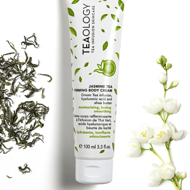 TEAOLOGY Jasmine Tea Firming Body Cream 100ml Tube, umgeben von Jasminblüten und Teeblättern.