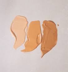 Drei Farbtöne von flüssiger Foundation auf einer hellen Oberfläche.