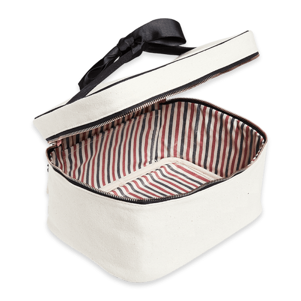 Geöffnete weiße Kosmetiktasche mit gestreiftem Innenfutter und schwarzem Reißverschluss.