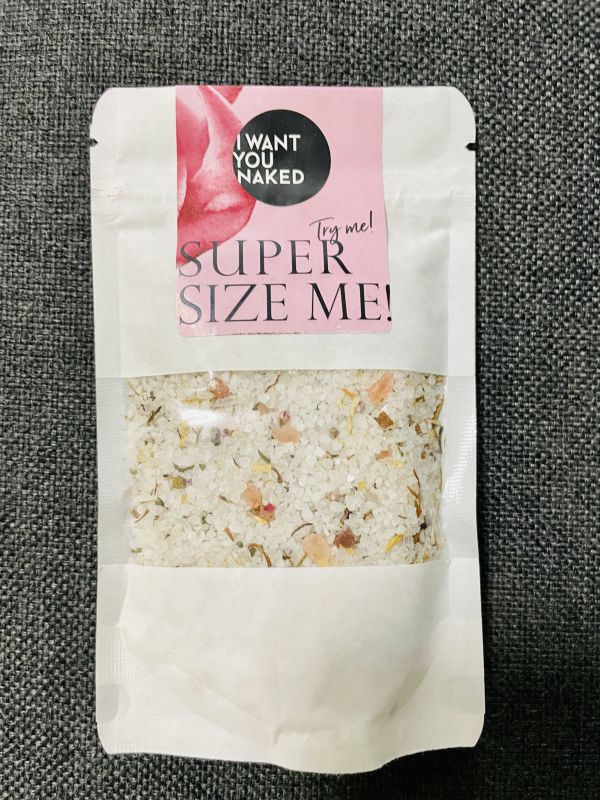 Eine Packung Badesalz mit der Aufschrift 'I WANT YOU NAKED SUPER SIZE ME!' auf einem grauen Hintergrund.